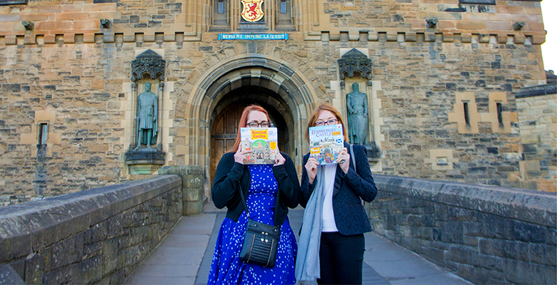 Two publishers posing in front of the entrance to Edinburgh Castle with copies of the new children's books