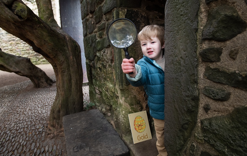 A child exploringing a castle with a magnifying glass during an Easter egg hunt event