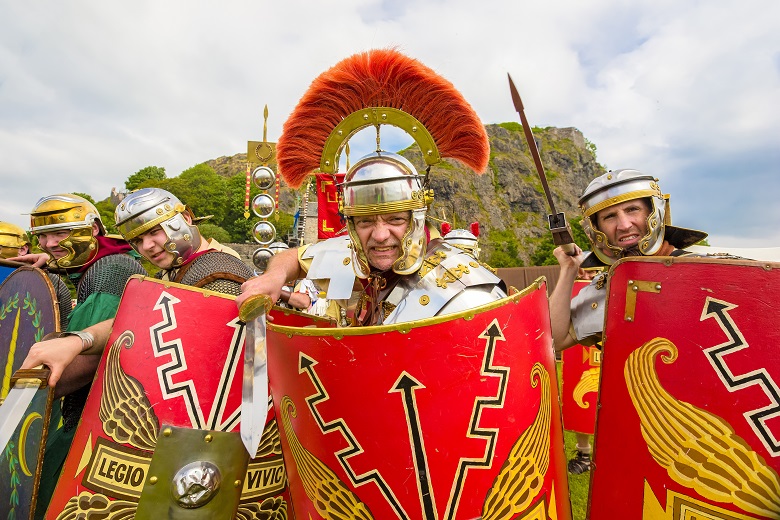 Reenactors dressed as Romans pose in front of Dumbarton Rock