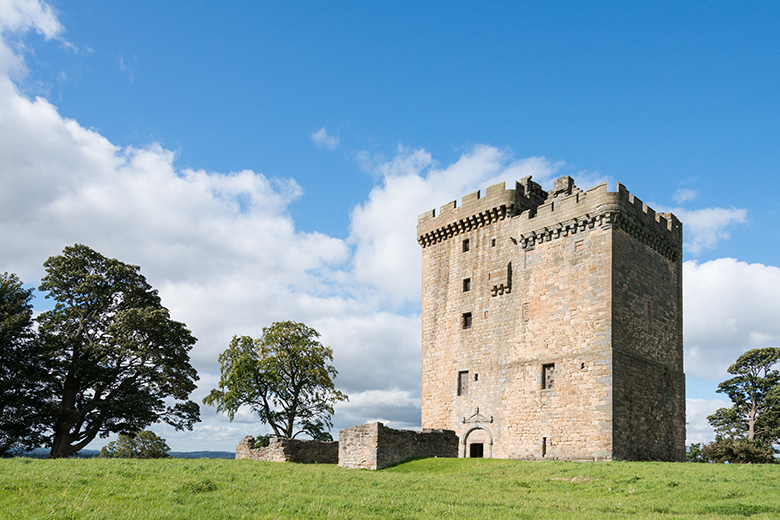 view of a towerhouse against a blue sky with some fluffy clouds