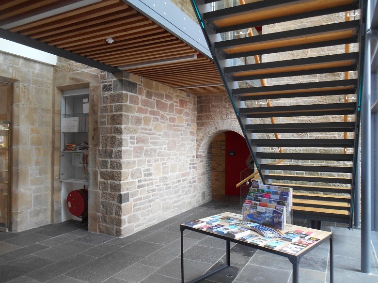 Renovated interior of the Borders Distillery building with exposed brickwork, a modern staircase and tiled floor. 