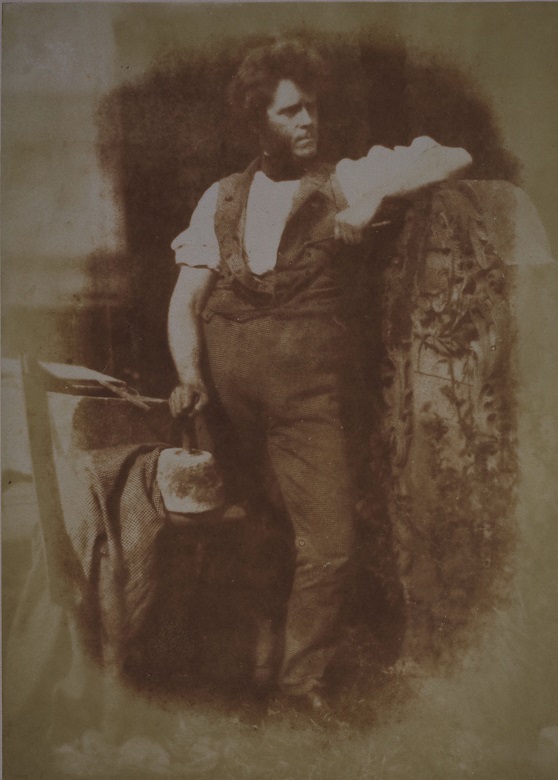 Archive image of Hugh Miller working beside a standing stone or gravestone 