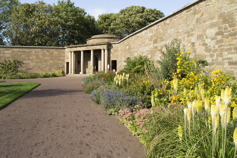 Interior of a well-kept walled garden with a temple-like structure in one corner