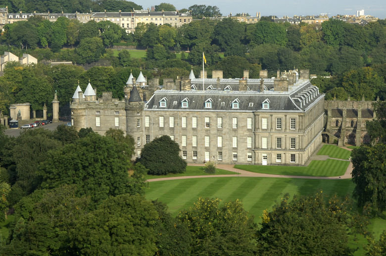 A view of Holyrood Palace with terraced houses and the Firth of Forth in the background 