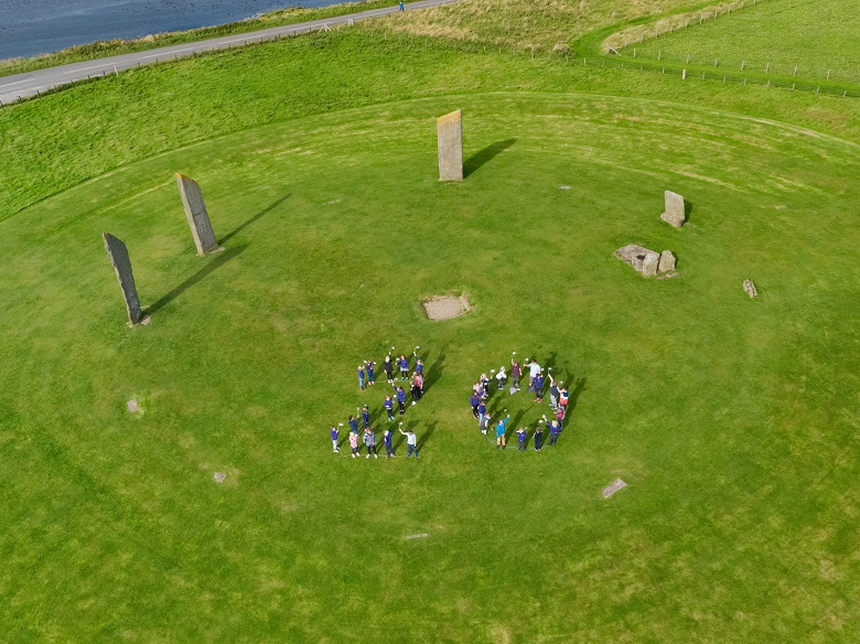 Children form a number 20 in the middle of a stone circle 