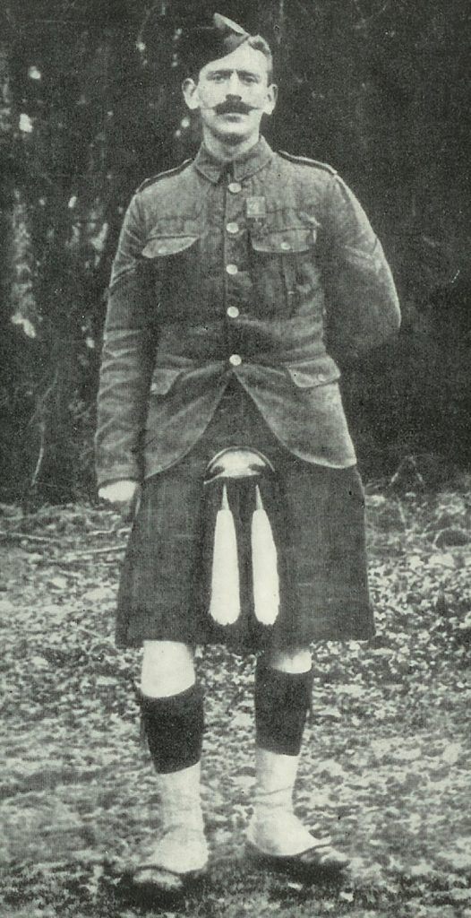 A full length image of a man with a moustache in his army uniform, wearing the kilt.