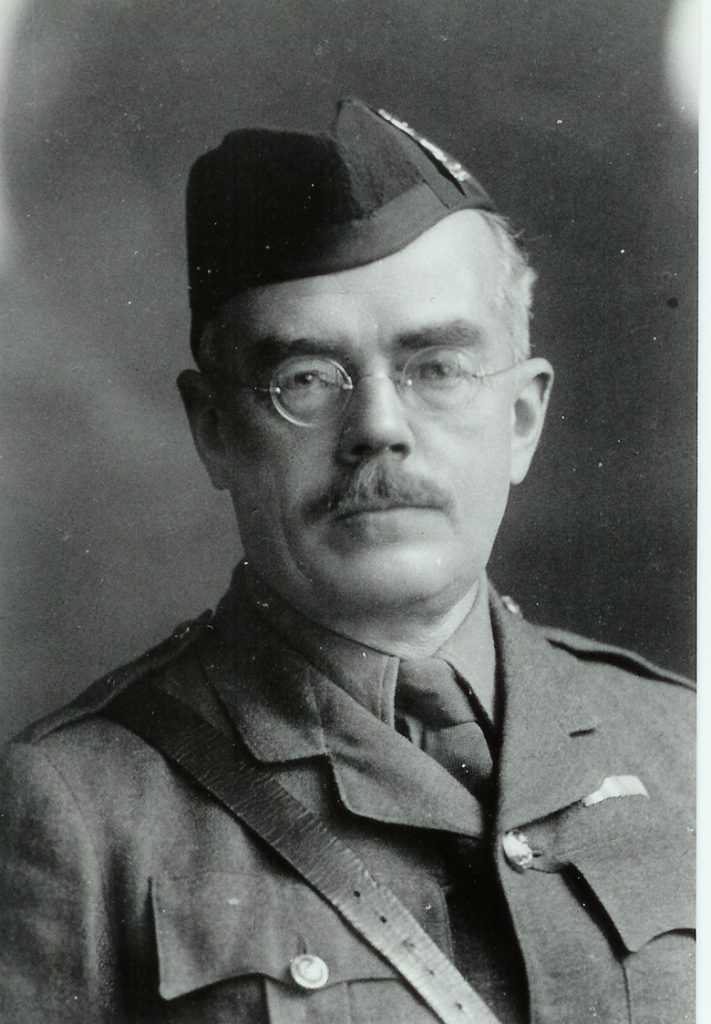 Portrait of a man in military uniform wearing glasses with a moustache.