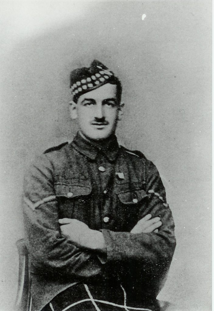 portrait of a man in military uniform sitting with his arms crossed over his chest. He has a moustache.