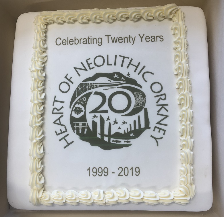 A white cake with a logo marking 20 years of the Heart of Neolithic Orkney on it 