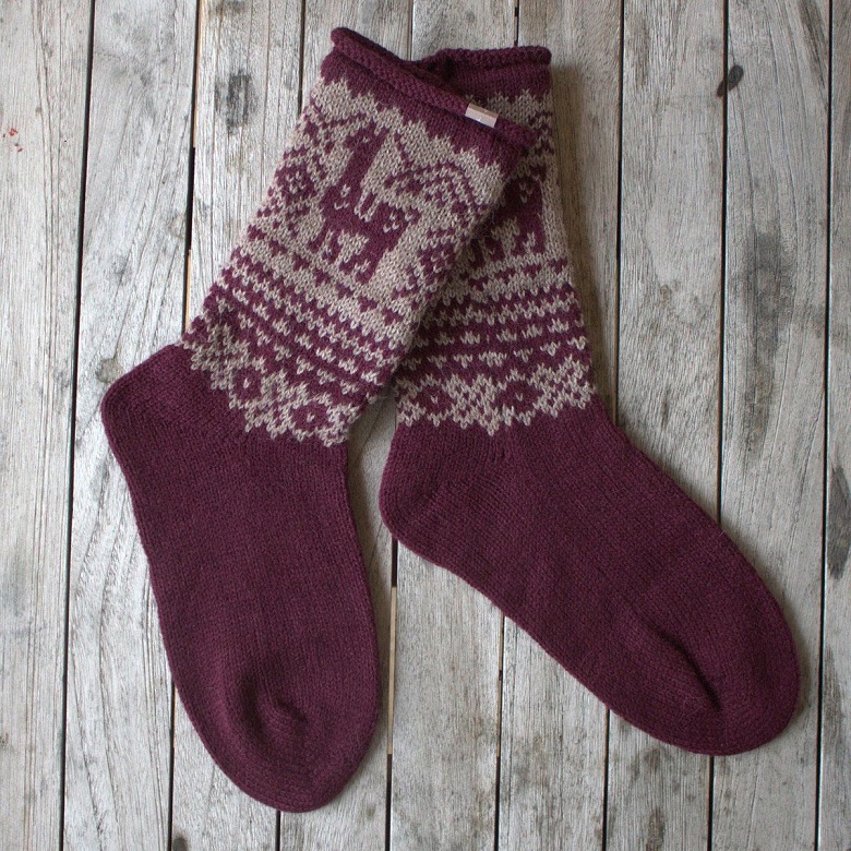 A pair of red knitted socks featuring an alpaca design 