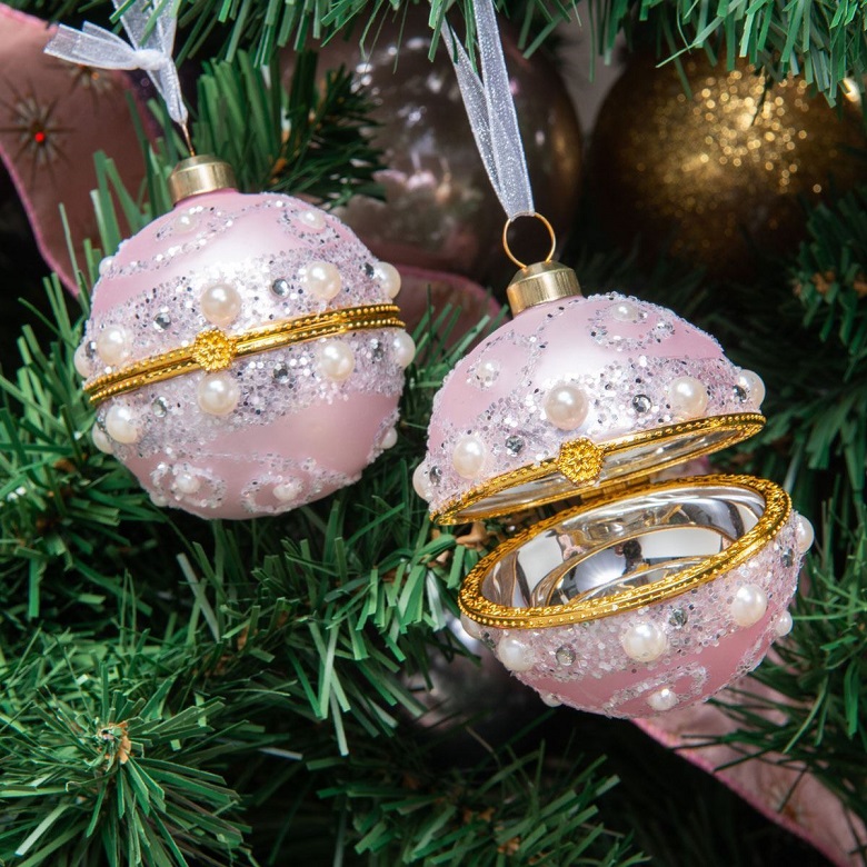 Two pink and gold baubles hanging from a Christmas tree 