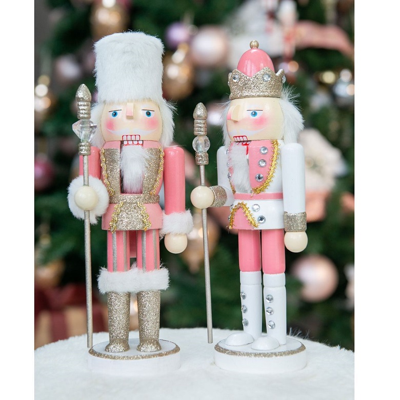 A pair of wooden Christmas nutcracker figures wearing pink outfits