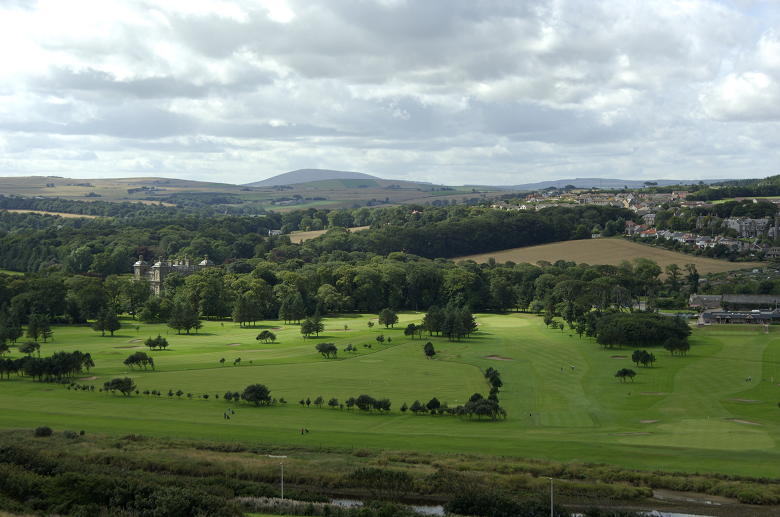 View from a hilltop of a golf course and stately home and distant hills