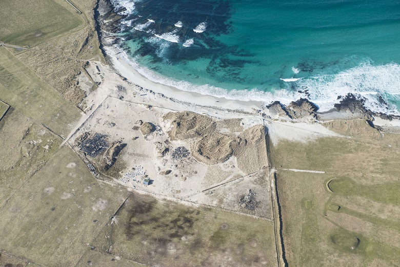 An aerial photo historic settlement by the sea. The coast is being eroded away.