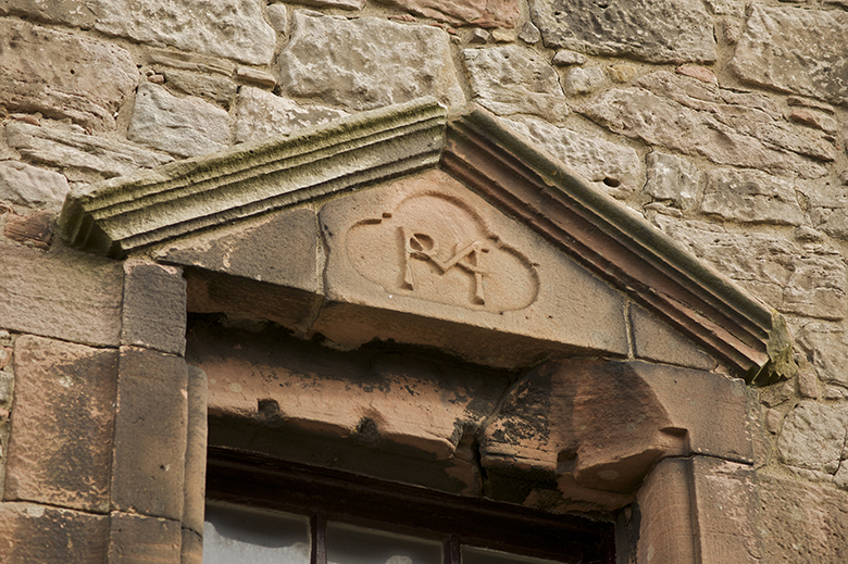 A carved window lintel with the letters M, M and C. 
