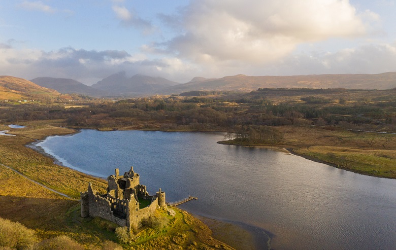 Drone photo of Kilchurn Castle beside Loch Awe with cloud-covered mountains in the background