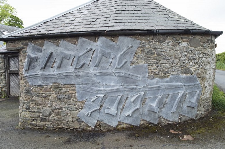 Lead depictions of axes on a stone wall near the entrance to The Steading 