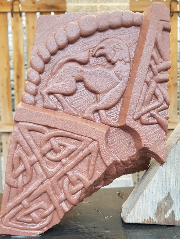 Close up shot of a replica of a Pictish carved stone centring on a griffin-like creature 