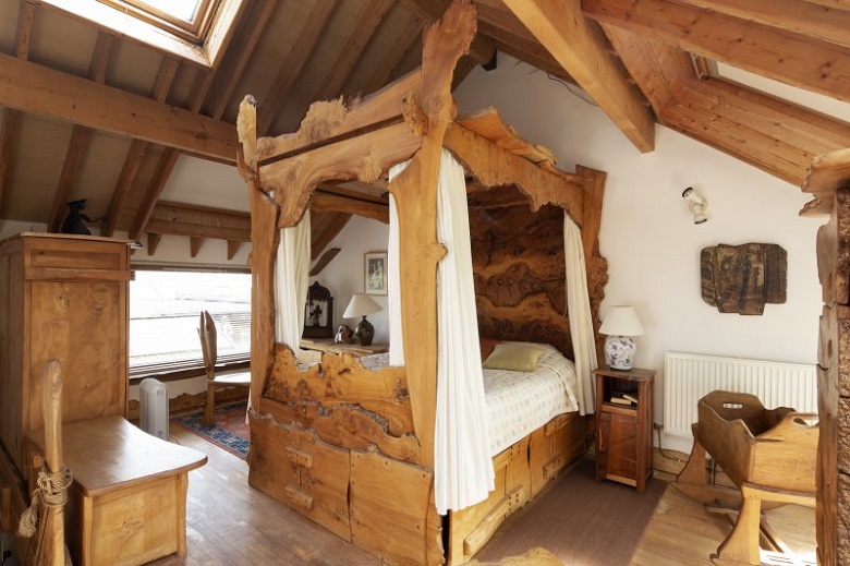 A large four-poster bed carved entirely from wood in one of the bedrooms at The Steading