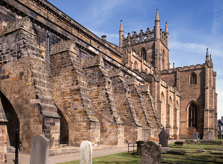 The exterior of Dunfermline Abbey and church, including a square tower with large stone lettering spelling out Robert the Bruce's name