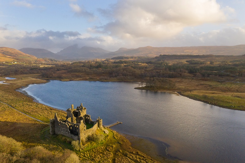 Drone photo of Kilchurn Castle and Loch Awe with sun shining on the ruins 