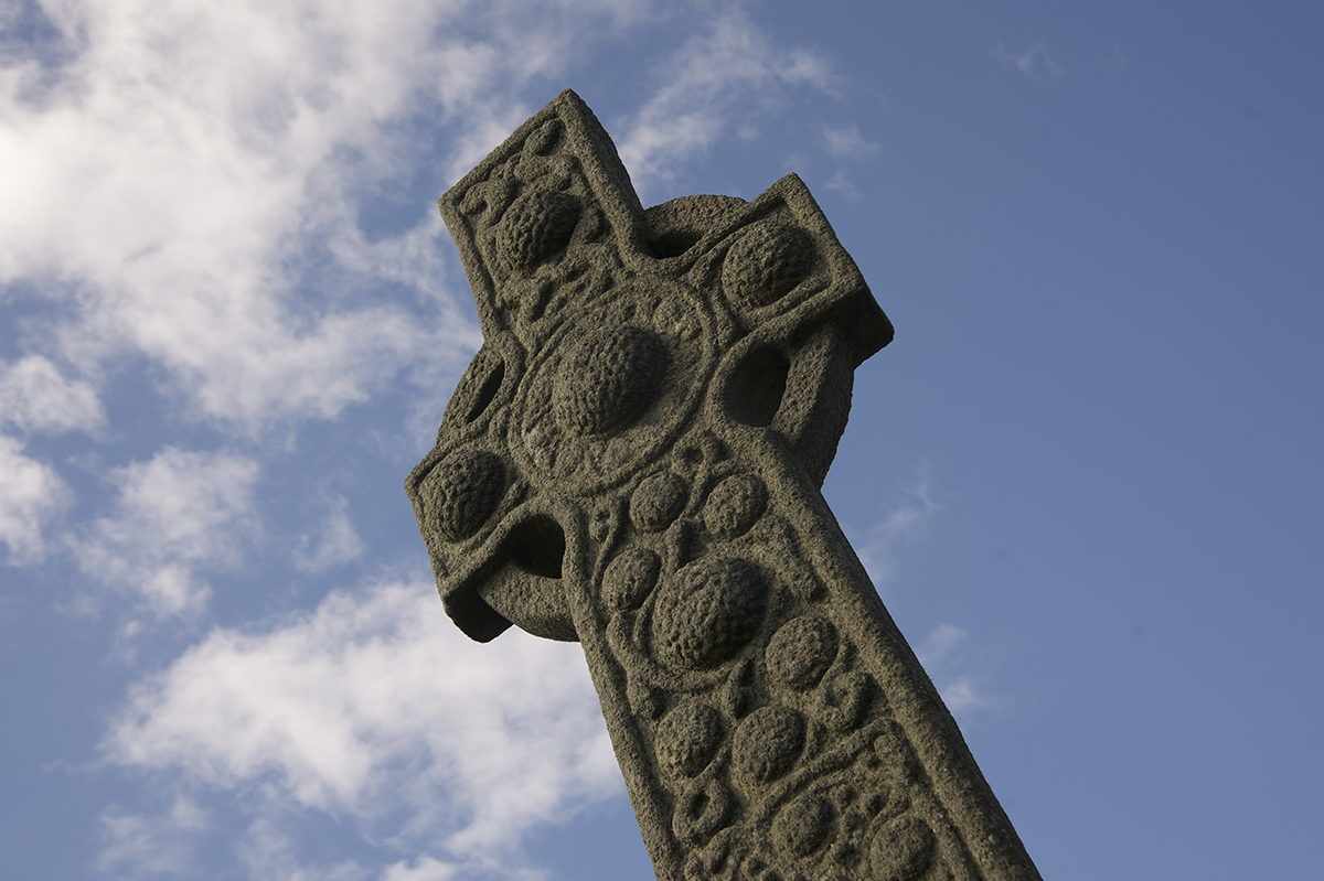 carved stone cross with blue sky behind it