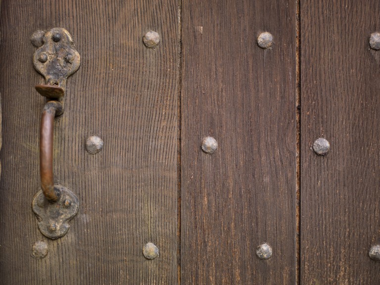 brown wooden door studded with nails