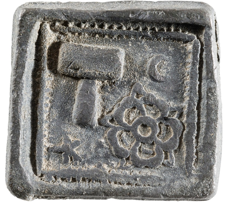 A square token with a decorative edge, featuring a rose and hammer.