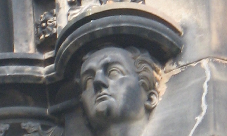 Close up of a stone carving of a young man's face 