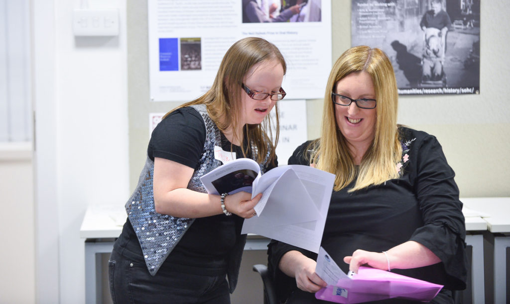 A woman with Down's Syndrome shows another woman a booklet