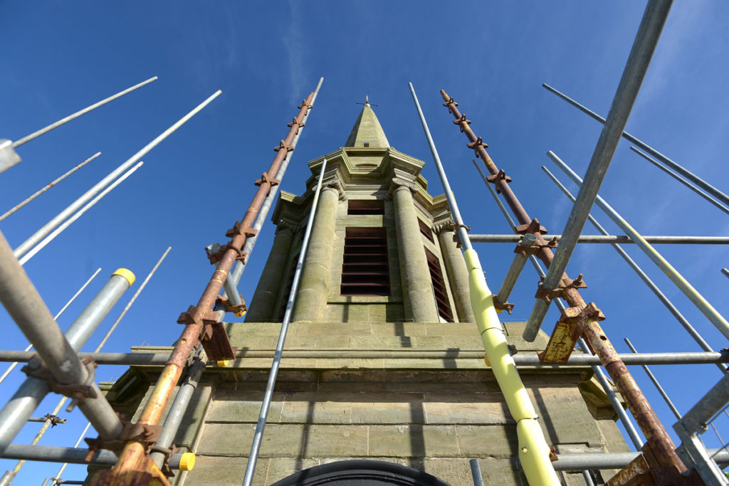 A tall building with a spire, surrounded by scaffolding