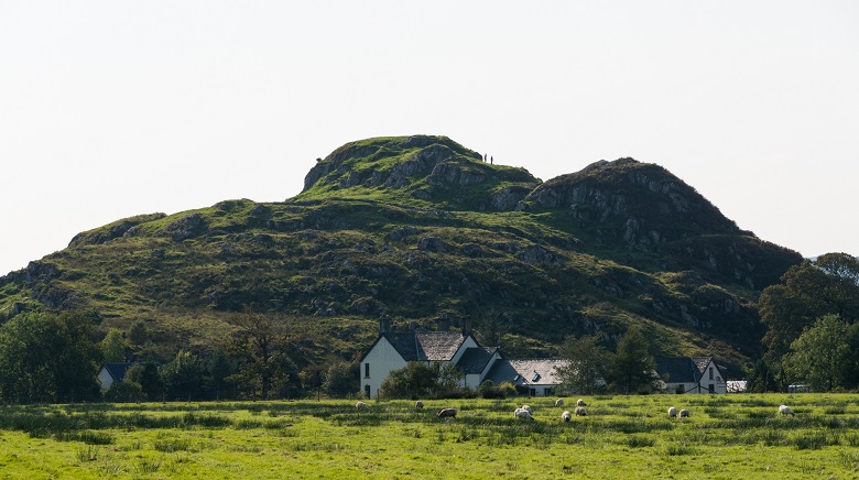 Houses and farmland in front of a rocky outcrop, once a hill fort 