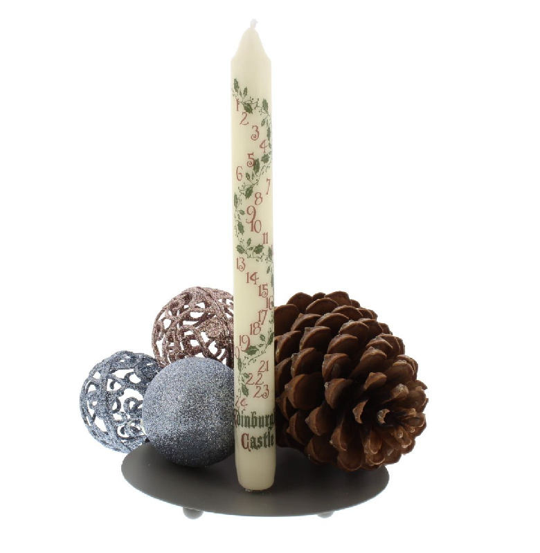 unlit candle with numbers 1-24 printed down the length of it, with a pine cone and christmas baubles at base