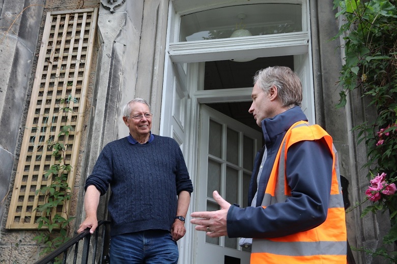 A person in high vis vest speaking to a homeowner