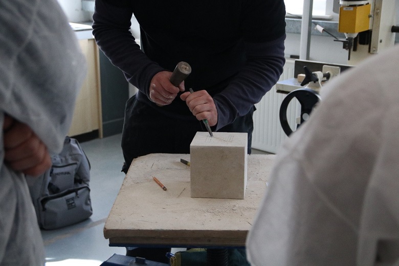 A person carving into a square block of stone