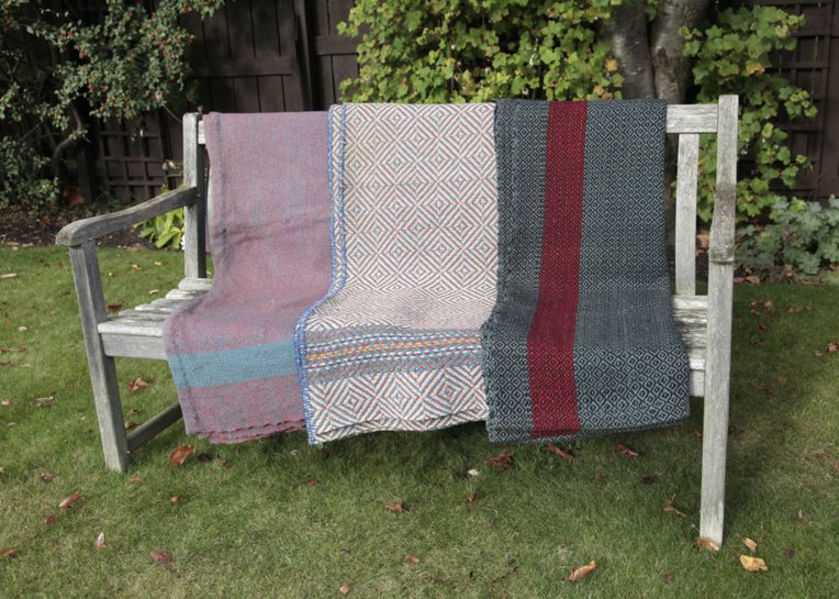 three blankets draped over a garden bench