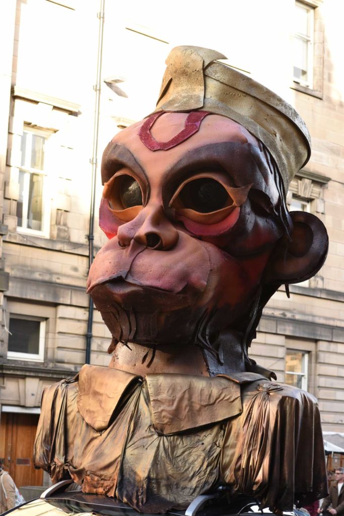 A large carnival effigy of a monkey being carried above the crowd in Edinburgh
