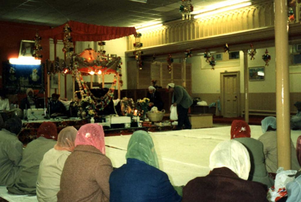 Women wearing headscarves sit in a decorated community building