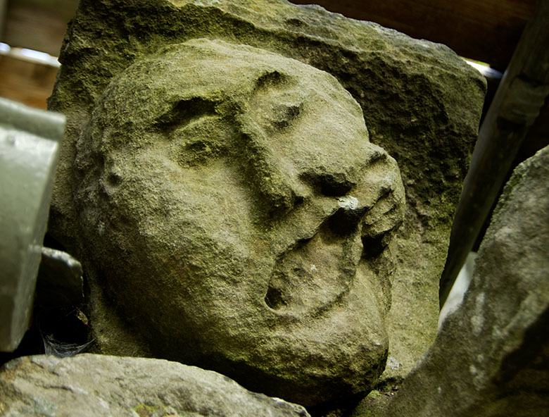 a simple carved face. A small had reaches around the side of its head, pulling the moth up to one side.