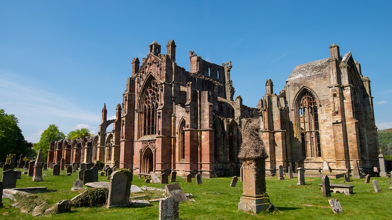 The ruins of an abbey with gravestones and memorials in the foreground