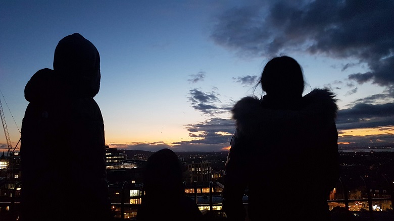 Silhouette of a family staring out to the horizon of Edinburgh at twilight 
