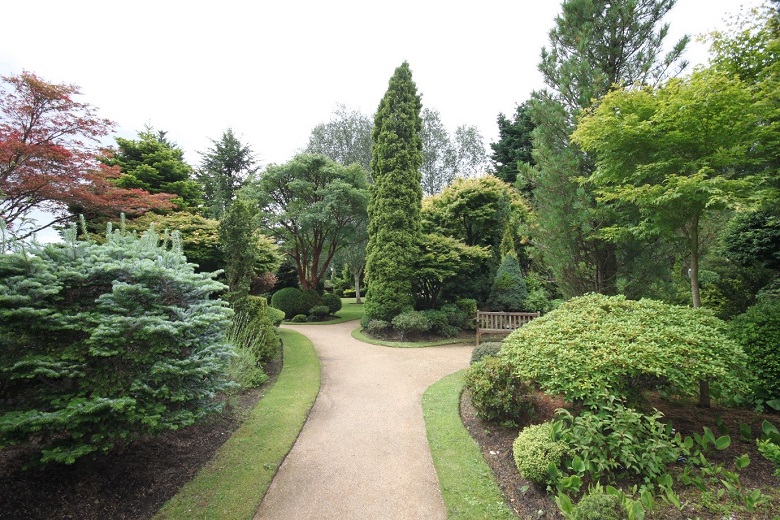 A path leading past flower beds and shrubs in a walled garden