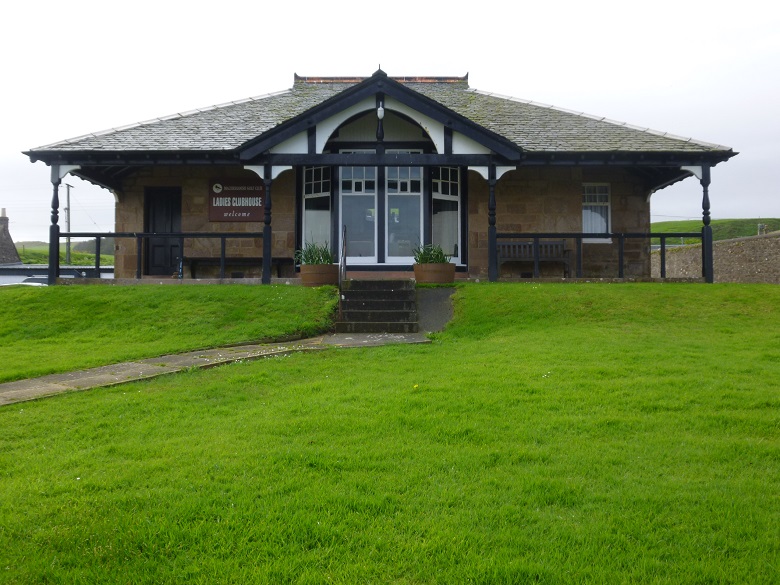 A single storey golf clubhouse decorated with black and white timber posts and a veranda 