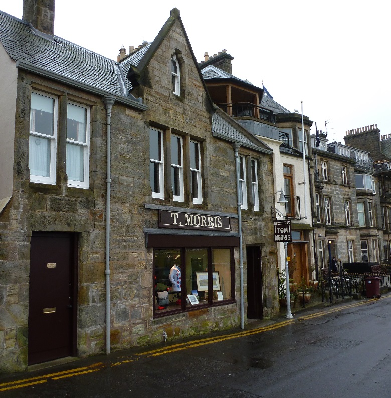 A small golf shop on a street in the town of St Andrews. The shop sign reads "T Morris" 