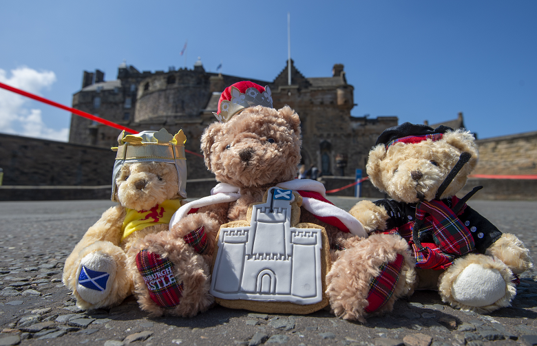 Three soft toy teddy bears photographed in front of Edinburgh Castle