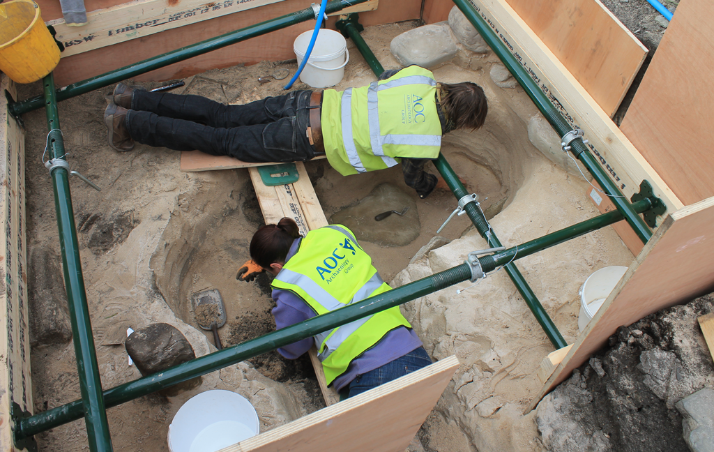 two people lying on scaffold looking into a trench