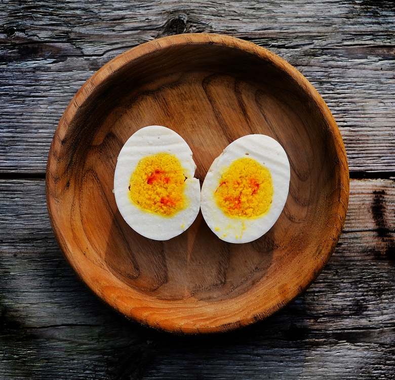 What appears to be a halved boiled egg served in a wooden bowl - on closer inspection the "egg" has been recreated using other, sweet ingredients