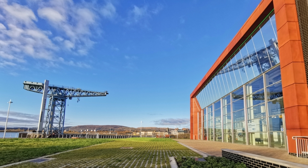 A crane faces a more modern, environmentally friendly building.