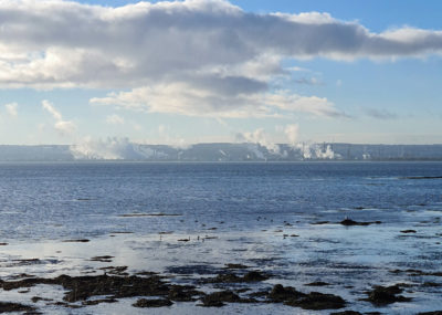 A view of the sea with industrial clouds in the background