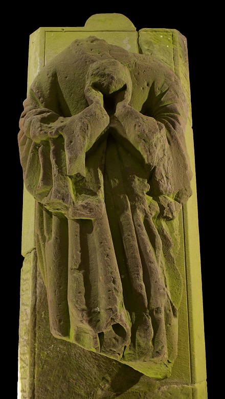A stone effigy, whihc has lost its head, showing a woman holding a heart to her chest